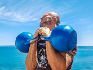 Man Lifting Pair of Blue Kettlebells